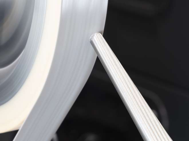 Close-up of the grinding belt of a MEPSA robotic cell during the grinding of a hip prosthesis
