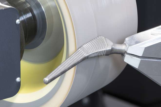 Close-up of a grinding belt on a MEPSA CNC machine grinding a hip prosthesis